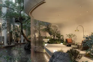 A modern living space with a waterfall, pond, and natural light, decorated with plants, chairs, and a dining table, featuring stone, glass, and wood materials in a dimly lit atmosphere