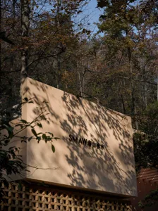 Photograph of a wooden cabin in a forest setting with tan-colored wood and natural light from the sun