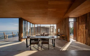 A warm and inviting restaurant dining area with a wooden floor, multiple dining tables, and natural light from windows