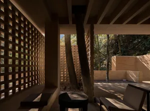 Outdoor living area with a stone wall and wooden bench, surrounded by natural surroundings and well-lit with natural light