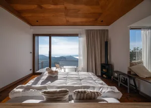 A calm and inviting bedroom with a bed and chair near a window, well-lit by natural light