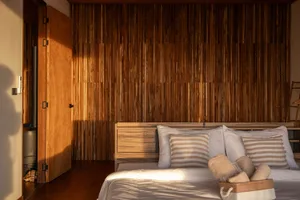 Dimly lit bedroom with a wooden wall and headboard, featuring a bed with two pillows