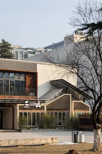 A modern building with a large white concrete wall and a tree in front, creating a calm and serene atmosphere