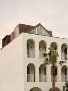 A modern villa with a red roof, balcony, and palm tree, set against a bright and sunny background