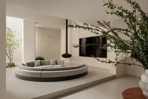A modern living room with a circular couch, television, and potted plant, featuring marble and wood materials and well-lit with a comfortable atmosphere
