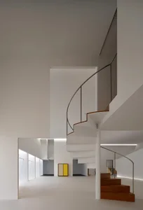 A wooden staircase with a metal railing in a bright and inviting hallway with a door at the bottom of the stairs