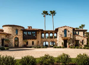 Spanish-style house with a brick exterior, stucco details, and a courtyard with a pool and fountain