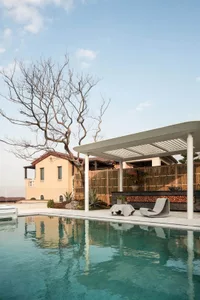 A backyard living space with a pool, patio, and gazebo, surrounded by a wooden fence and featuring natural materials and warm sunlight