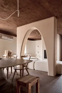Cozy living room with a white couch, dining table, and chair, surrounded by natural light and a vaulted ceiling