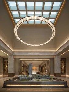 A large, open room with a high ceiling, a circular light fixture, and a predominantly white color scheme, creating a clean and inviting atmosphere