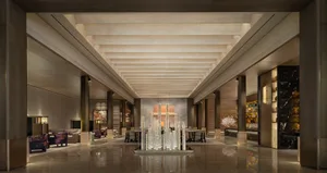 A well-lit, modern room with a high ceiling, wood furniture, and a chandelier, creating a warm and inviting atmosphere