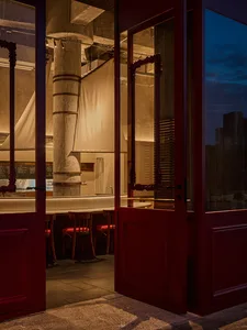Cozy restaurant with a red door, white counter, and dim lighting, featuring a dining area with a table and chairs