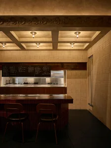 A warm and inviting restaurant interior with a wooden counter, brick elements, and soft lighting