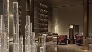 A well-lit modern living room with a brown couch, chair, coffee table, and decorative items, surrounded by bookshelves and a warm atmosphere