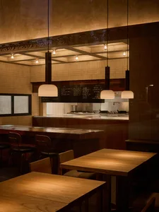 Dining area with wooden tables and chairs, illuminated by lights, creating a warm and inviting atmosphere
