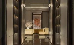 A well-lit room with a marble floor, a large couch, a dining table, and a vase with flowers, giving a luxurious and sophisticated atmosphere