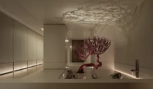 A modern room with white walls, a red tree-like sculpture, and natural light from windows