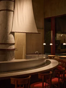 Cozy modern restaurant interior with a bar, wooden and stone elements, and a unique sail-like structure