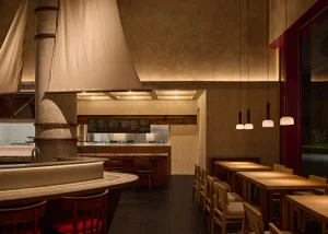 A well-lit restaurant interior with modern wood and tile elements, dining tables, chairs, and tableware