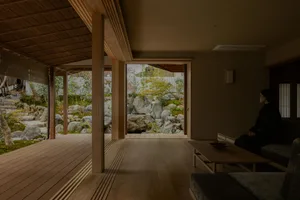 Cozy living room with a wooden floor, a couch, a chair, and a dining table, lit by dim warm lighting