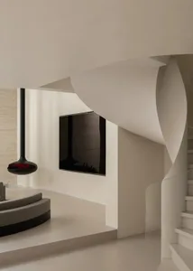 Modern minimalist interior featuring a sculptural curved white staircase, floating black pendant light, built-in TV, and curved grey sofa against textured concrete walls.