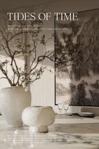 Elegant dining area featuring a large black and white Chinese ink painting of misty mountains, a fluted wall panel, textured ceramic vases with dried branches, and a marble dining table set with crystal glassware.