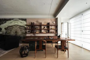 Modern dining room featuring a solid walnut table, matching Chinese-style armchairs, dark green marble base, and a dramatic large-format marble art wall with built-in walnut shelving.