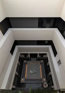 Top-down view of a modern architectural atrium with a sunken stone courtyard, recessed lighting, and surrounding white and dark grey walls.