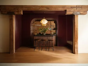 Luxurious home bar with deep burgundy walls, reclaimed wood beams, arched brick niche, fluted wood bar front, and three velvet bar stools.