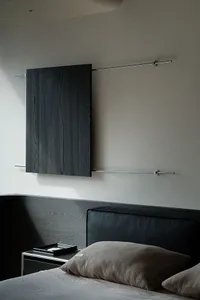 Modern minimalist bedroom featuring a black oak floating headboard and matching wall-mounted console, paired with a black leather headboard and neutral textured pillows.