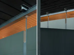 Close-up view of a modern office partition system featuring sage green panels, warm wood ceiling, and exposed steel suspension hardware.