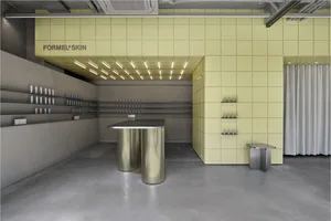 現代美容零售空間，萊姆綠穿孔金屬天花板與牆面，不鏽鋼圓柱展示台，以及水泥地板。