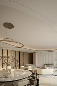 Modern luxury open-plan living and dining area featuring a large round white marble dining table, sculptural circular pendant light, curved ceiling, and neutral-toned contemporary furniture.