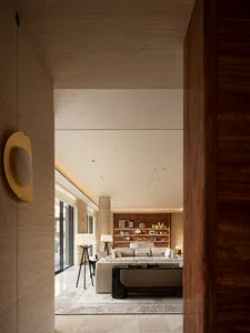 Modern luxury living room featuring travertine walls, a large cream sectional sofa, dark wood bookshelf, and layered lighting.