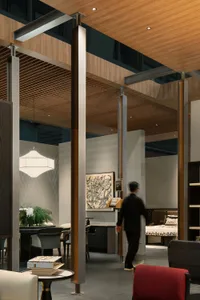 Modern commercial showroom interior with wooden ceiling slats, concrete structural columns, architectural model display, dining area, and bed vignette in the background.