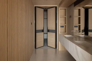 Modern minimalist bathroom interior with double white marble sinks, oak vanity, large mirror, and a prominent light oak fluted wood wall panel on the left.