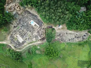 Aerial photograph of a large construction site with building foundations and concrete frames in a rural area surrounded by green forest and rice paddies in Taiwan.
