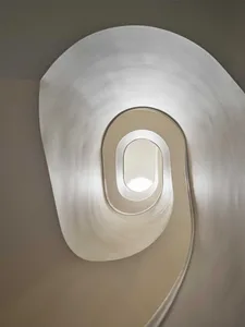 View looking down into a sculptural white spiral staircase with smooth organic curves and integrated lighting.