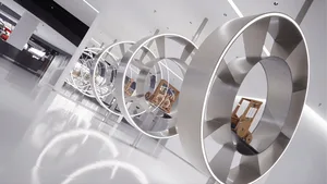 Large-scale stainless steel circular sculptures arranged in a receding tunnel formation inside a modern white exhibition space with reflective floors.