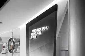 Monochrome interior of a technology pavilion featuring an illuminated 3D sign reading TECHNOLOGY PAVILION with Chinese characters, set against minimalist white walls and metallic circular structures.