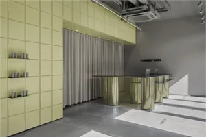Modern retail reception area with curved brushed-metal desk, lime green padded acoustic wall panels, and grey curtain backdrop.