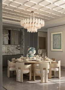 Luxurious dining room featuring a large round marble-top table surrounded by six mother-of-pearl inlaid dining chairs, a large white capiz shell chandelier, marble floor, and grey cabinetry with a floral centerpiece.