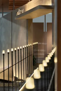 Modern concrete staircase featuring a continuous row of warm LED lights integrated into the black metal railing, with illuminated vertical posts creating a glowing pathway effect.