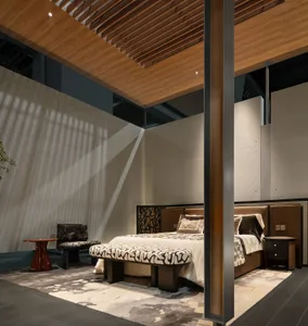 Modern luxury bedroom featuring a walnut slatted ceiling, concrete accent wall with dramatic sunlight shadows, upholstered bed with patterned bench, and layered neutral textiles.
