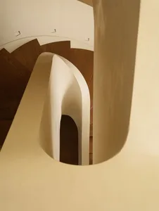 View looking down a modern curved staircase featuring smooth off-white plaster walls and balustrade paired with dark oak wooden treads and recessed ceiling lighting.