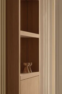 Close-up of a modern minimalist built-in wooden shelving niche made of light oak with two small wooden objects on the lower shelf.