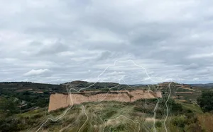 Wide landscape view of the Loess Plateau in China featuring eroded earthen hills, green vegetation, and a large white abstract topographic wave graphic overlay under a cloudy sky.