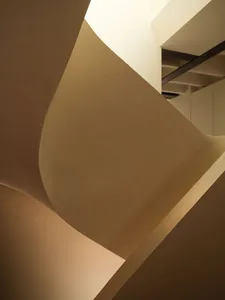 Close-up view of a sculptural curved plaster staircase with smooth organic forms and warm neutral tones.