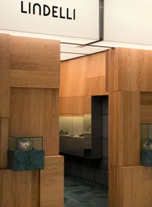 Modern jewelry boutique interior featuring light oak wood paneling, dark green marble bases, glass display cases, and integrated lighting.