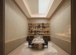Modern minimalist home library with light oak wood paneling, built-in illuminated bookshelves, marble oval table, dark green textured armchairs, and a large skylight.